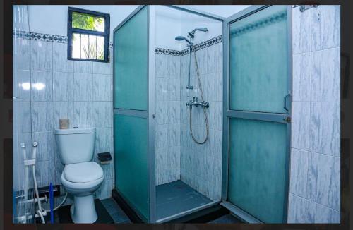 a bathroom with a toilet and a glass shower at Elsy Villa Negombo in Negombo