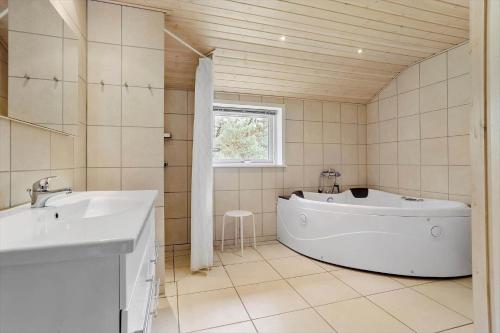a bathroom with a tub and a sink and a window at 0317-Romo-Sonderstrandvej-24 in Høm