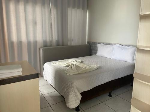 a small bedroom with a bed with white sheets at Flat Centro 302 in Tangara da Serra