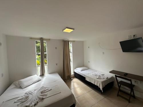 a bedroom with two beds and a desk and a television at Pousada Vila Catarina in Ouro Preto