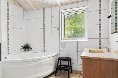 a white bathroom with a tub and a window at 0390-Romo-Lyngvejen-45-A in Høm