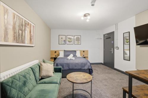 a living room with a green couch and a bed at Clayton Apartments in Newcastle upon Tyne