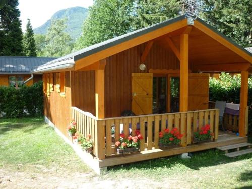 a small wooden house with flowers in a yard at ZEcamping 3 étoiles animaux acceptés restaurant et Canoë Kayak in Aigueblanche