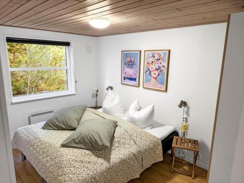 a bedroom with a bed with pillows and a window at 2801-Romo-Helmusager-4 in Høm