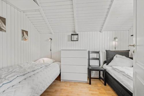 a bedroom with two beds and a dresser and a chair at 0386-Romo-Vestergade-3-Ap-16 in Høm