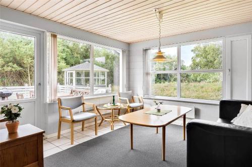 a living room with a table and chairs and windows at 0357-Romo-Sonderstrandvej-21 in Høm
