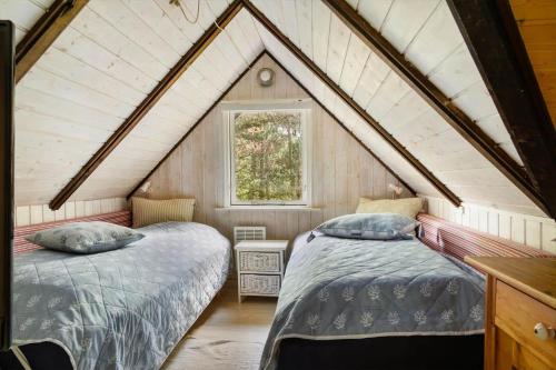 a attic bedroom with two beds and a window at 0337-Romo-Kliren-1 in Høm