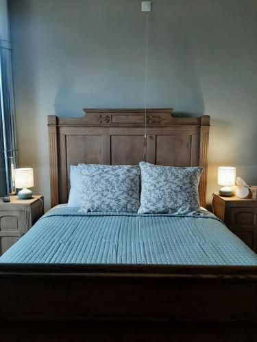 a bedroom with a bed with a wooden headboard and two lamps at L'Ultra Pause au cœur du Viroin in Olloy-sur-Viroin