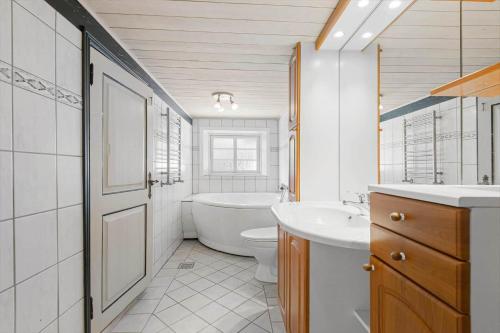 a bathroom with a tub and a toilet and a sink at 2001-Romo-Juvrevej-80 in Høm