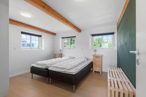 a bedroom with a large bed in a room with windows at 2001-Romo-Juvrevej-80 in Høm