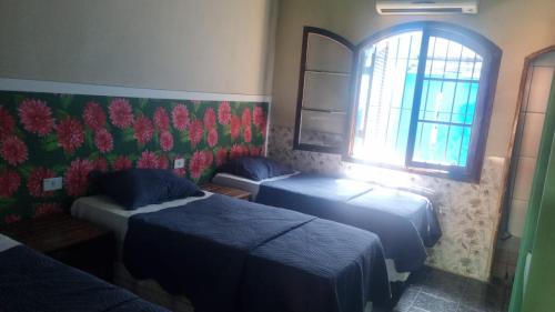 a room with two beds and a window at Pousada TURI in Caraguatatuba