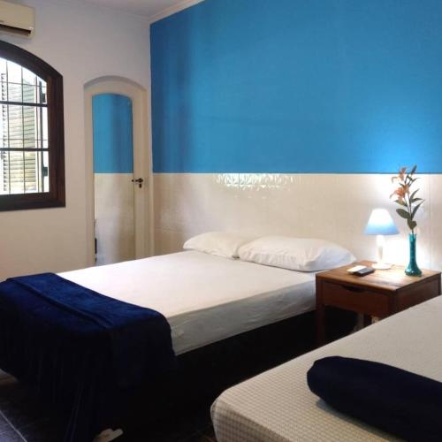 a bedroom with two beds and a blue wall at Pousada TURI in Caraguatatuba