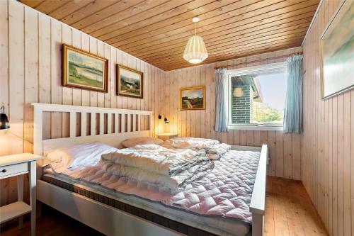 a bedroom with a large bed in a room with wooden walls at 0028-Romo-Blabaervej-28 in Høm