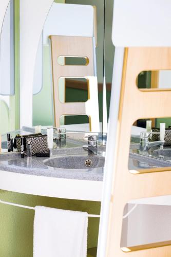 une salle de bain avec un lavabo et un miroir dans l'établissement Ibis Budget Perpignan Nord Rivesaltes, à Rivesaltes