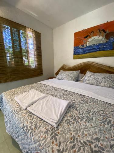 a bedroom with two beds and a painting on the wall at Jardín del Mango Nu in Zipolite