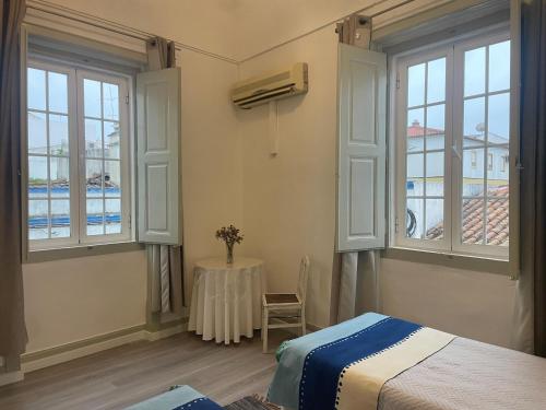 a bedroom with a bed and a table and windows at Casa Dona Joaquina in Reguengos de Monsaraz