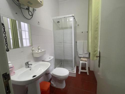 a white bathroom with a toilet and a sink at Casa Dona Joaquina in Reguengos de Monsaraz
