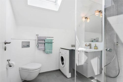 a white bathroom with a toilet and a washing machine at 0281-Romo-Vestergade-3-Ap-13 in Høm
