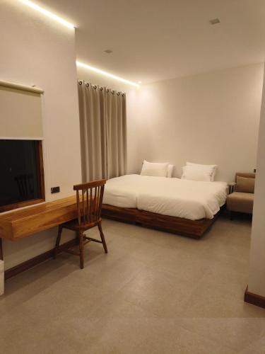 a bedroom with a bed and a television and a chair at เดอะมูนไลท์วิลล่าพะเยา in Phayao