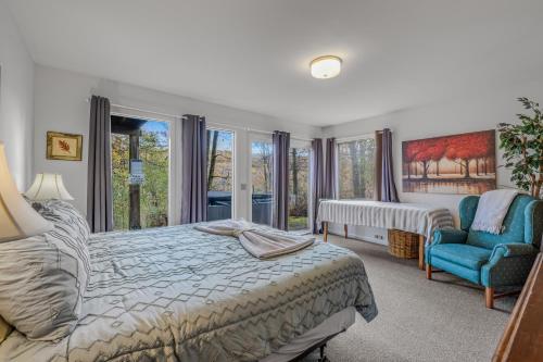 a bedroom with a bed and a chair and windows at Serendipity -- Hot Tub - Pet Friendly - Fire Pit - Grill - Porch - Deck - Wifi - Pool Access - Games in Berkeley Springs