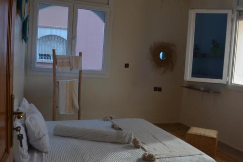 a bedroom with a bed and two windows at west wave surf house in Tamraght Ouzdar
