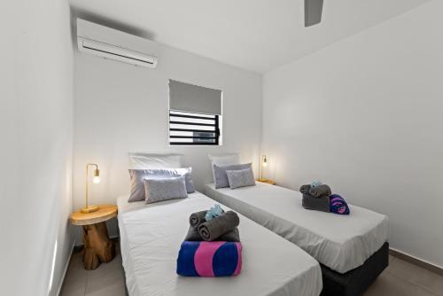 two beds in a room with white walls at Tropilena Resort in Willemstad