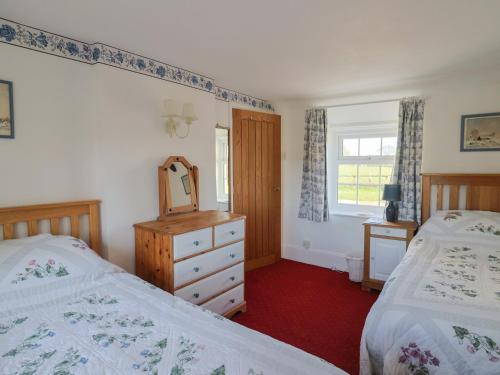 a bedroom with two beds and a dresser and a mirror at The Old Smithy in Bridport