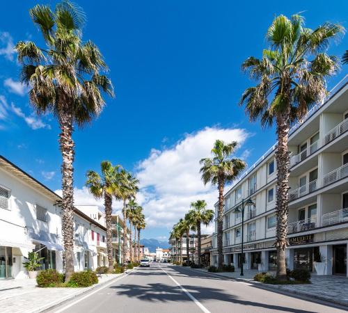 a street with palm trees and a building at Il Forte di Monic in Forte dei Marmi