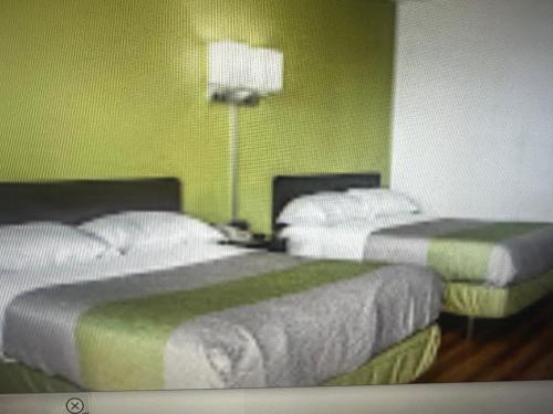 two beds in a room with green walls at Motel 6 El Paso East in El Paso