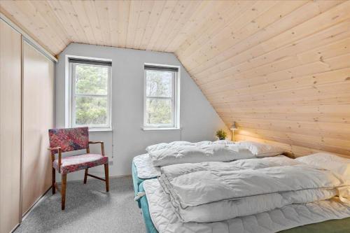 a bedroom with a bed and a chair and windows at 0185-Romo-Rabjergvej-82 in Høm