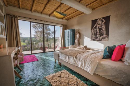 a bedroom with a bed and a large window at La Villa DUCASSE - Piscine, pétanque, calme à Essaouira in Essaouira