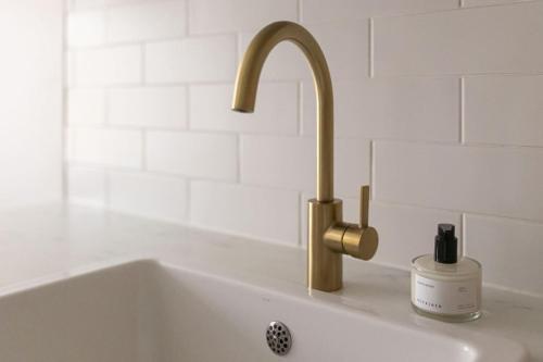a sink with a gold faucet and a bottle of soap at Seafront Country house with jacuzzi in Salo