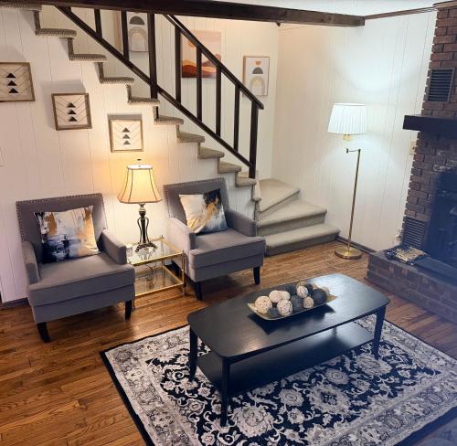 a living room with two chairs and a staircase at The Cozy Chalet in Asheville