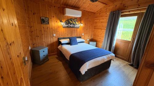a bedroom with a bed in a wooden cabin at Bryn Bettws Log Cabins Ltd in Port Talbot