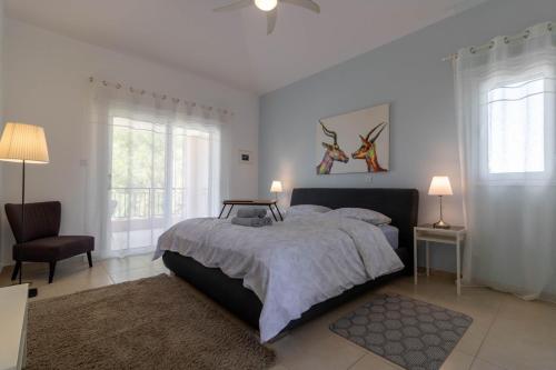a bedroom with a bed and a chair and windows at Villa Isla in Peyia