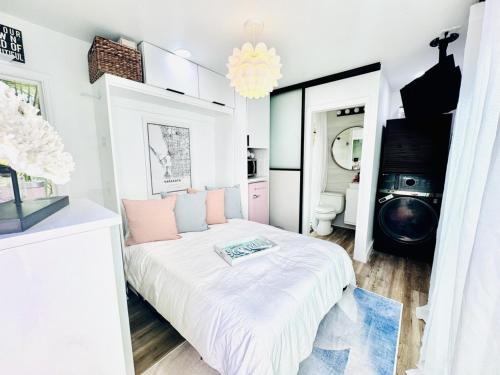 a white room with a bed with pink pillows at Walk to Siesta Key Beach-Remote Worker Friendly -High Speed WiFi- Bikes Included -Private Fenced In -Close to Restaurants, Coffee Houses & Shops - Paisleys Keep it Simple Casita in Siesta Key