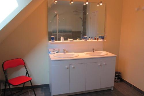 a bathroom with two sinks and a red chair at Maison moderne Le doux refuge des pêcheurs près de la mer à Cancale 3 étoiles in Cancale