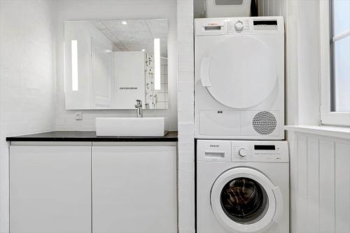 a white kitchen with a washing machine and a sink at 0119-Romo-Smafolksvej-43 in Høm