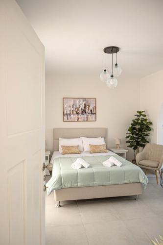 a white bedroom with a bed and a potted plant at Noméa - Modern Apartment Aigio in Aigio