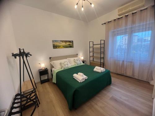 a bedroom with a green bed with towels on it at Le Camere di Don Nicó in Tarquinia