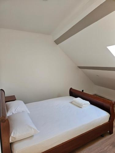 a bed with white sheets and two towels on it at Petite maison design proche centre ville in Cusset