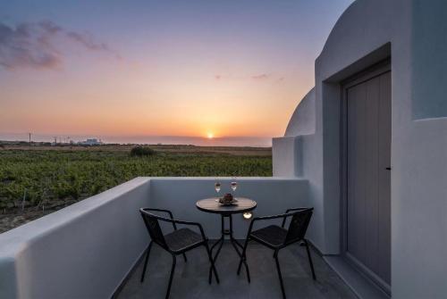 a balcony with a table and chairs and a sunset at MelivOia - Sunset Jacuzzi Villas in Foinikiá