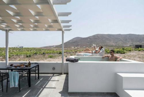 a couple of people in a bath tub with a table at MelivOia - Sunset Jacuzzi Villas in Foinikiá
