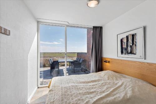 a bedroom with a bed and a balcony with a table at 1170-Romo-Gulirisvej-170 in Høm