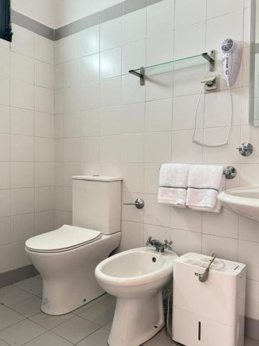 a white bathroom with a toilet and a sink at Habitación con terraza privada y vista a Funchal in Estrela