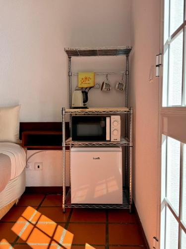 a microwave on a shelf in a room with a bed at Habitación con terraza privada y vista a Funchal in Estrela