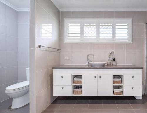 a white bathroom with a sink and a toilet at Lamington Cottage in The Range