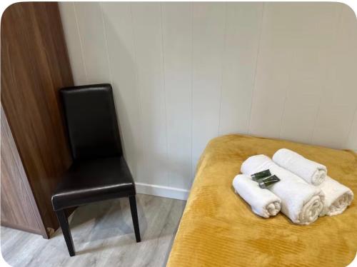 a bed with towels and a chair in a room at Couston Lakes Resorts in Bathgate