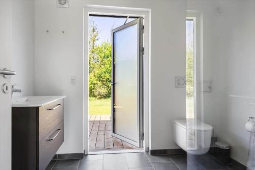 a bathroom with a toilet and a sink and a glass door at 0370-Romo-Vestergardsvaenget-13 in Høm
