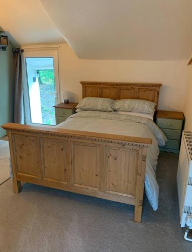 a bedroom with a large wooden bed and a window at Corner Lodge in North Tawton